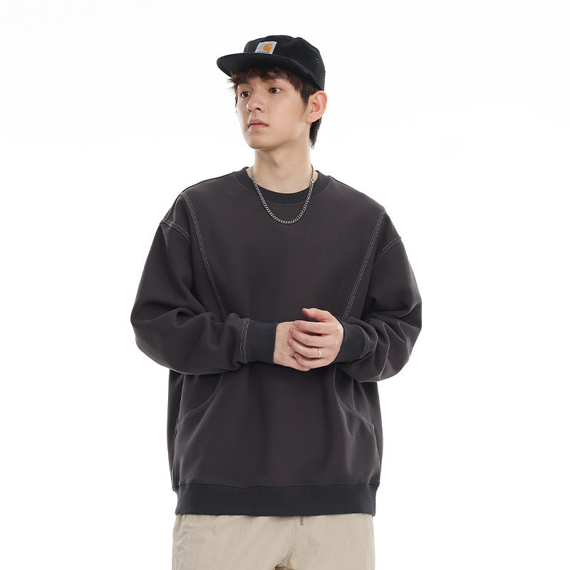 Model wearing a charcoal crewneck sweatshirt with contrast stitching, ribbed cuffs and hem, and curved front seams.