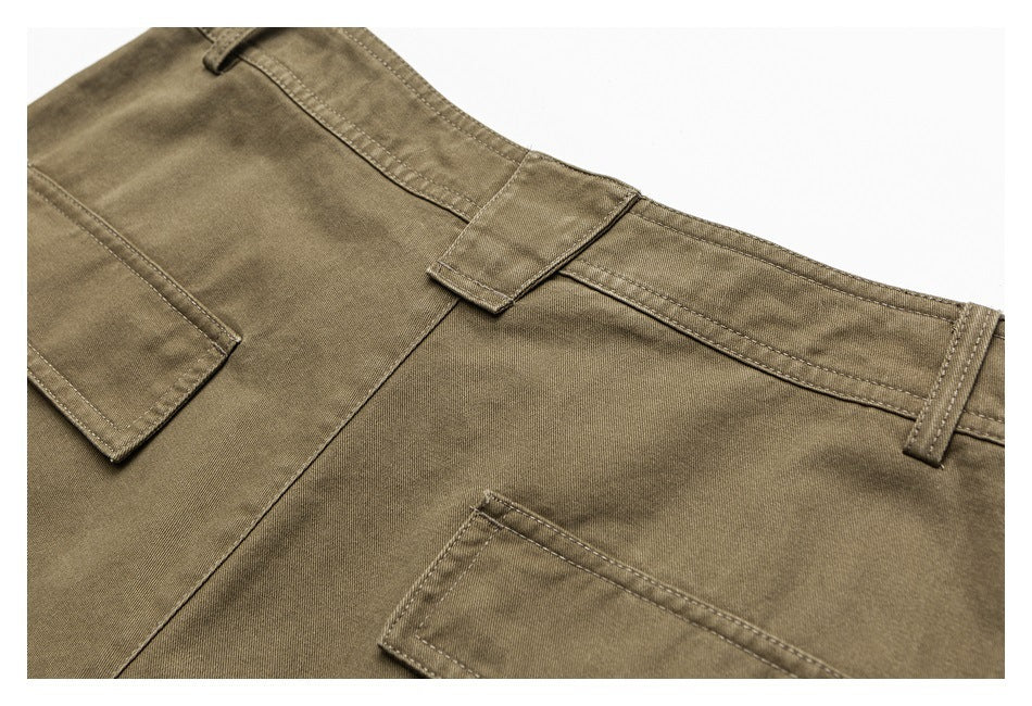 Close-up of olive-brown trousers showing the waistband, belt loops, seams and pocket edges.