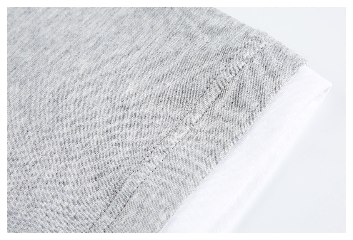 Close-up of light gray heathered fabric with a double-stitched seam beside a white edge.