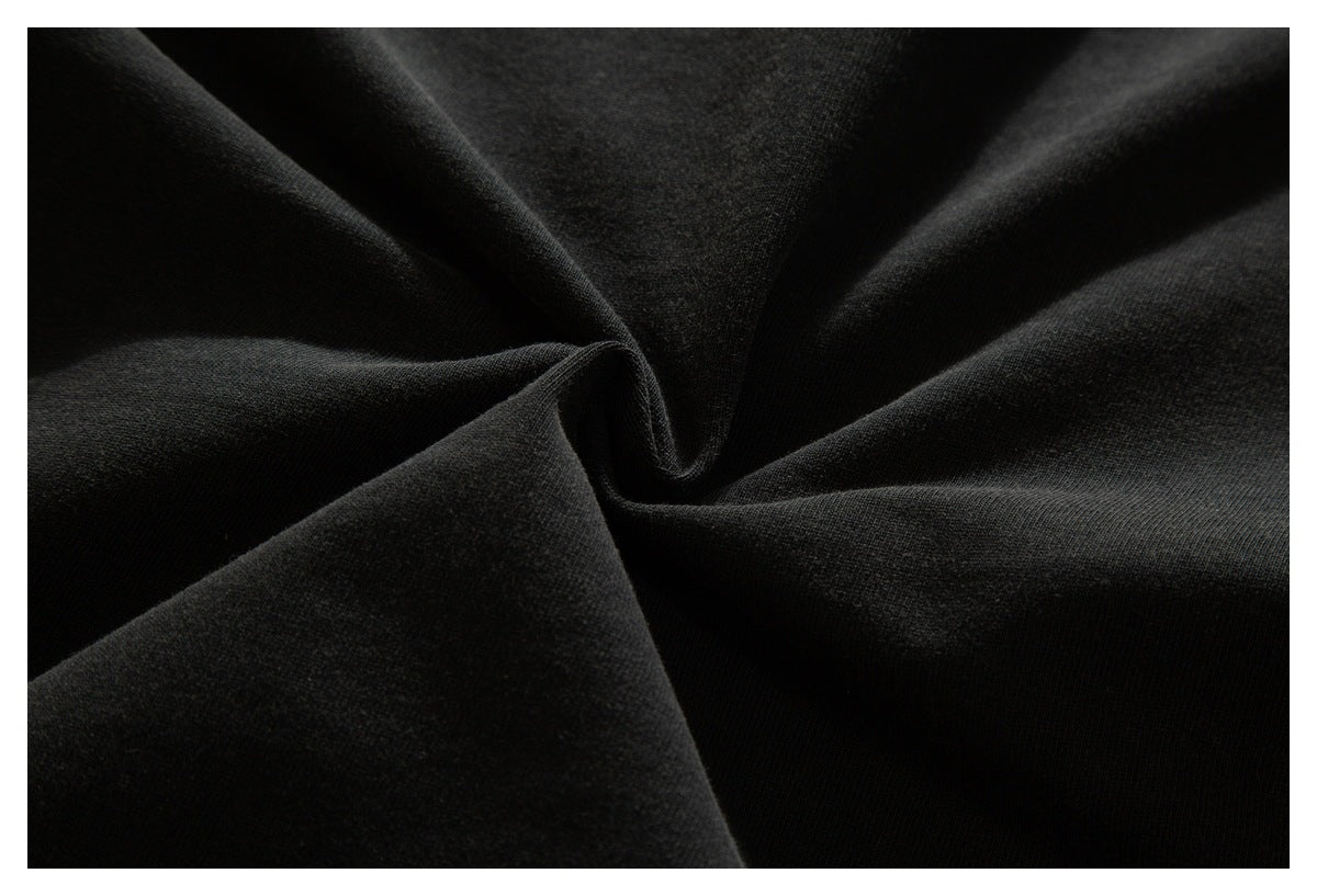 Close-up of dark black fabric gathered into soft folds, showing its surface texture.