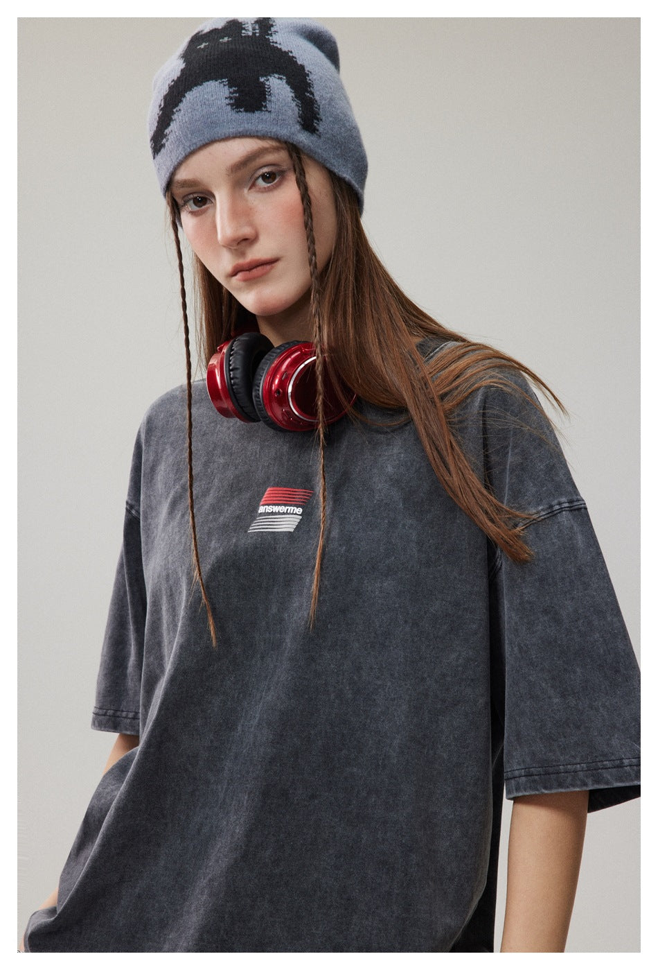 Close-up of a model wearing an oversized charcoal washed T-shirt with a small red-and-white chest graphic.