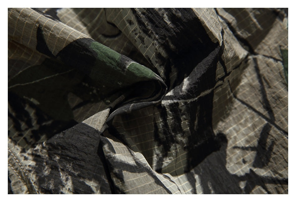 Extreme close-up of the shorts' dark green, brown, gray, and black camouflage fabric.