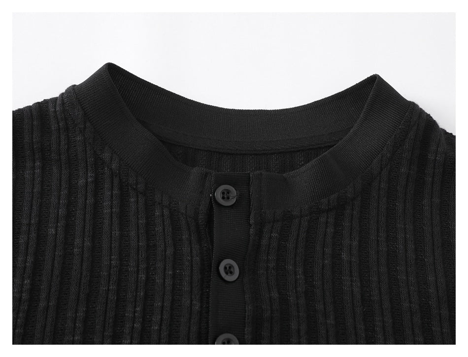 Close-up of the black ribbed shirt's rounded neckline and upper button placket.