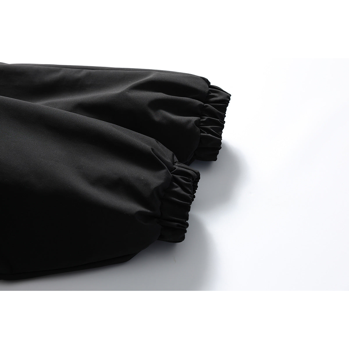 Close-up of the black jacket's gathered elastic cuffs on a white background.