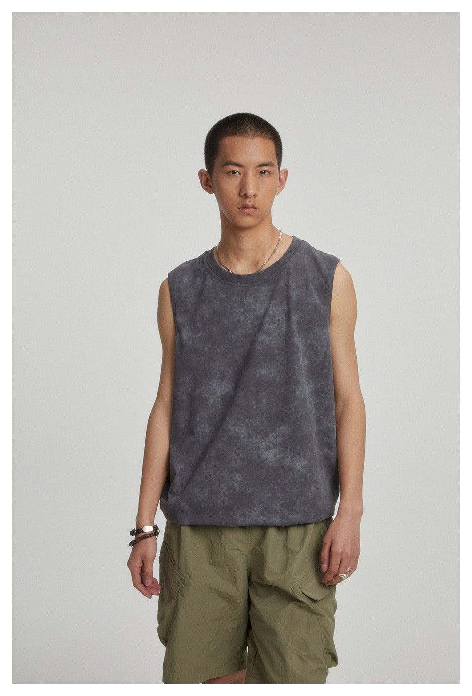 Model wearing a charcoal mottled sleeveless crewneck top and olive cargo shorts, facing forward.