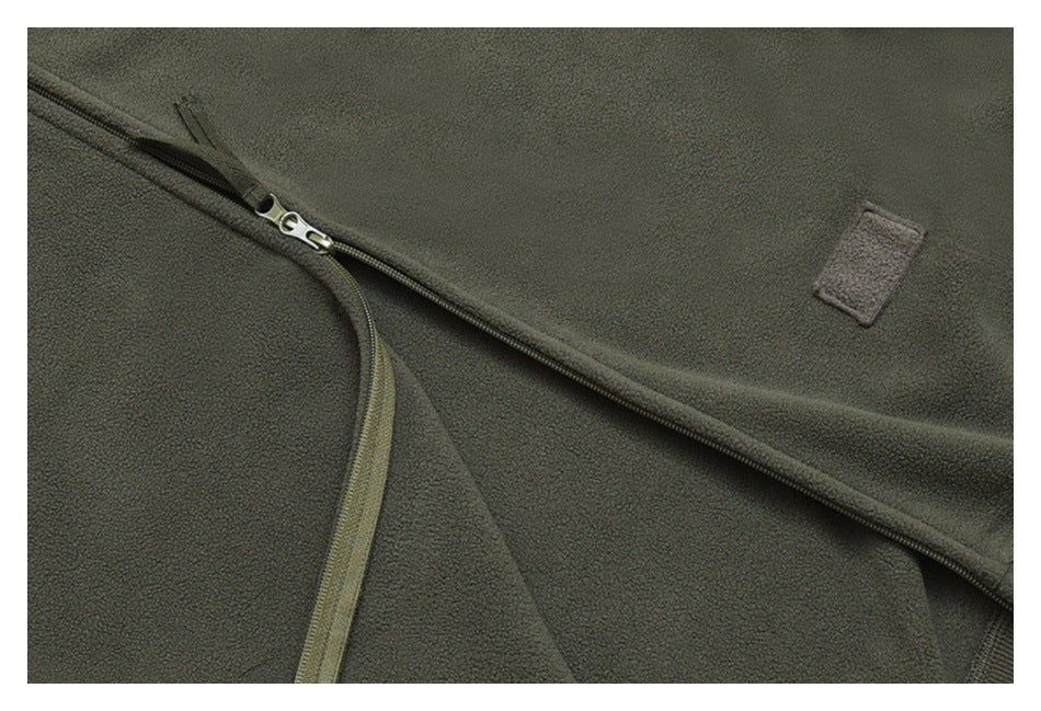 Close-up of the olive-gray jacket's zipper and a small blank rectangular patch.