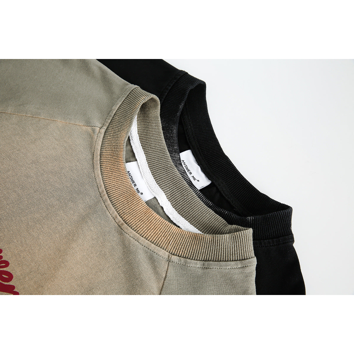 Close-up of khaki and black T-shirt collars with ribbed neckbands and visible inner labels.