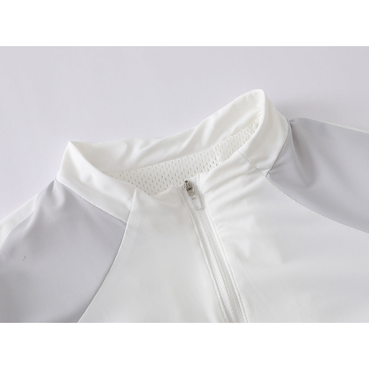 Close-up of a white zip-front jacket showing its stand collar, mesh inner collar panel, and light gray shoulder panels.