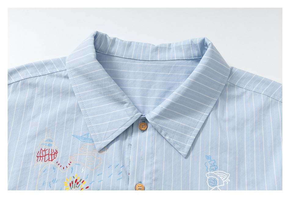 Close-up of the collar and upper front of a light blue pinstriped shirt with colorful embroidery and tan buttons.