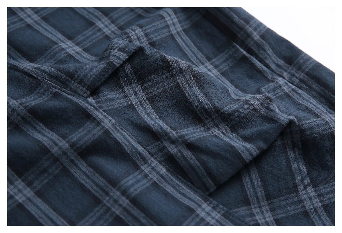Close-up of dark navy trousers showing a gray plaid pattern and folded fabric.