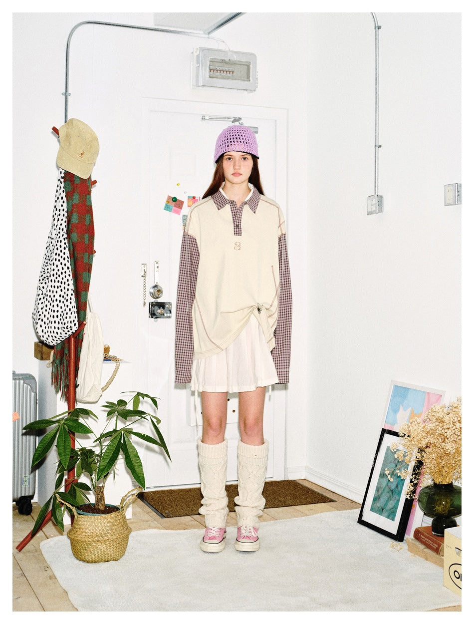 Model wearing the oversized apricot polo-style top with plaid sleeves and collar, white skirt, purple beanie and leg warmers