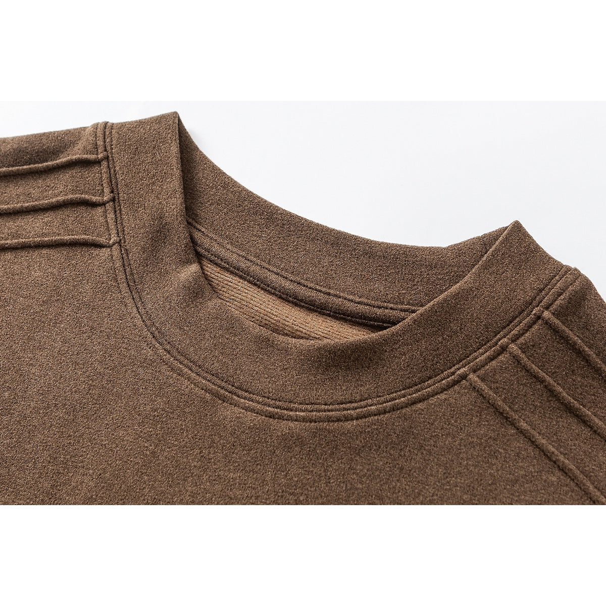 Close-up of a brown crewneck shirt showing the collar stitching and shoulder seam details.