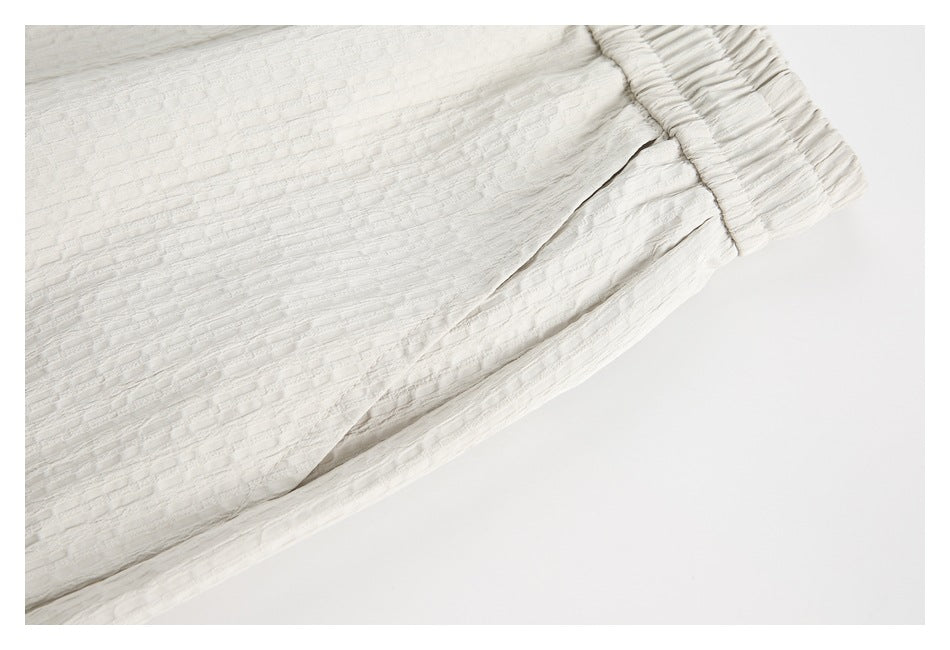 Close view of white textured shorts showing the side seam and gathered elastic waistband.