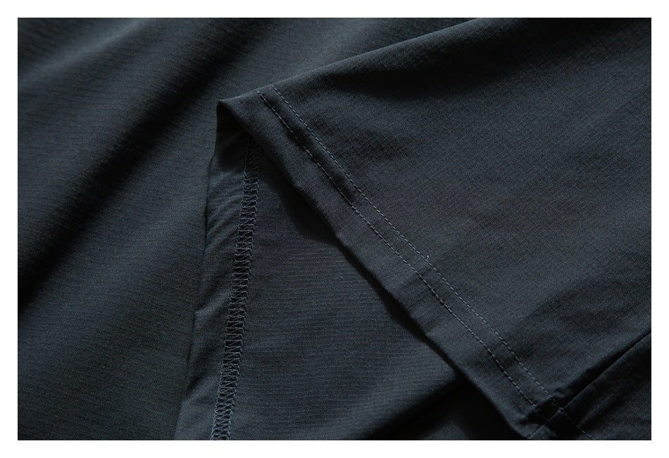 Close-up of black garment fabric showing an overlocked seam and double-stitched folded edge.