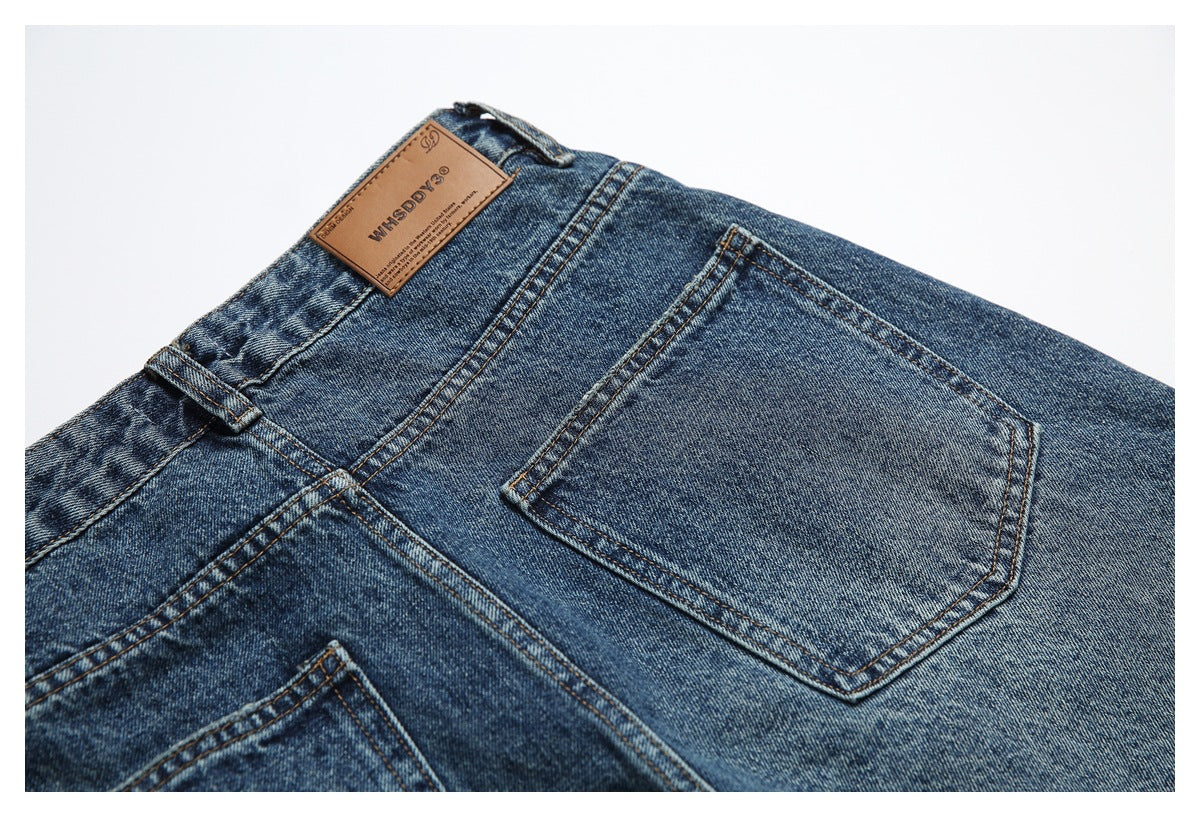 Close-up of blue jeans' back waistband and pocket, with a tan leather brand patch and belt loop.