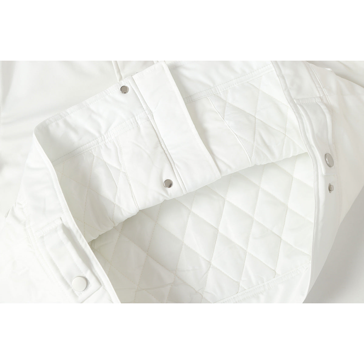 Close-up of the white jacket's diamond-quilted lining and silver snap fasteners.