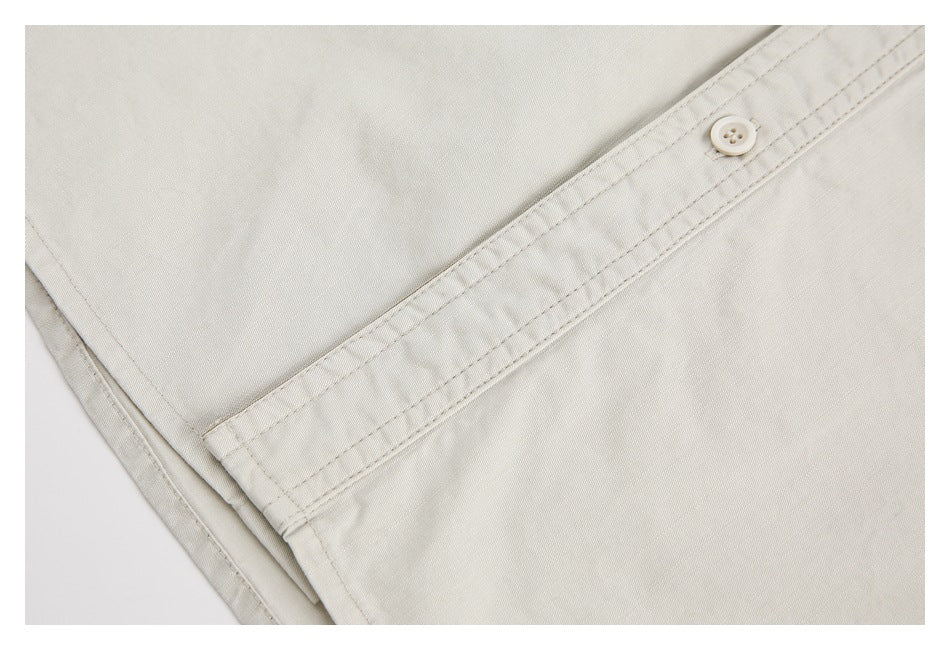 Close-up of an off-white shirt's stitched button placket and white button.
