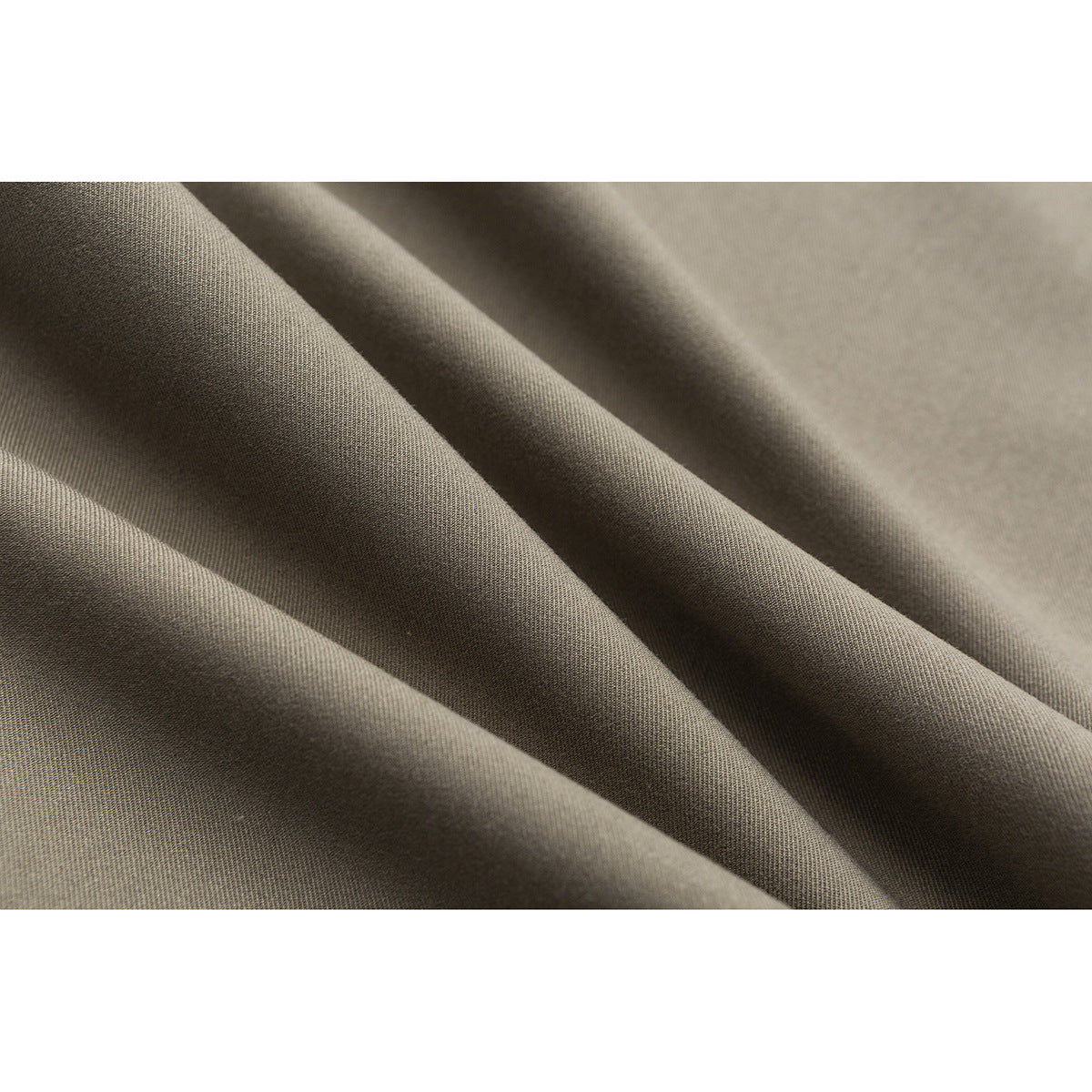 Extreme close-up of taupe fabric draped in folds, showing its fine woven texture.