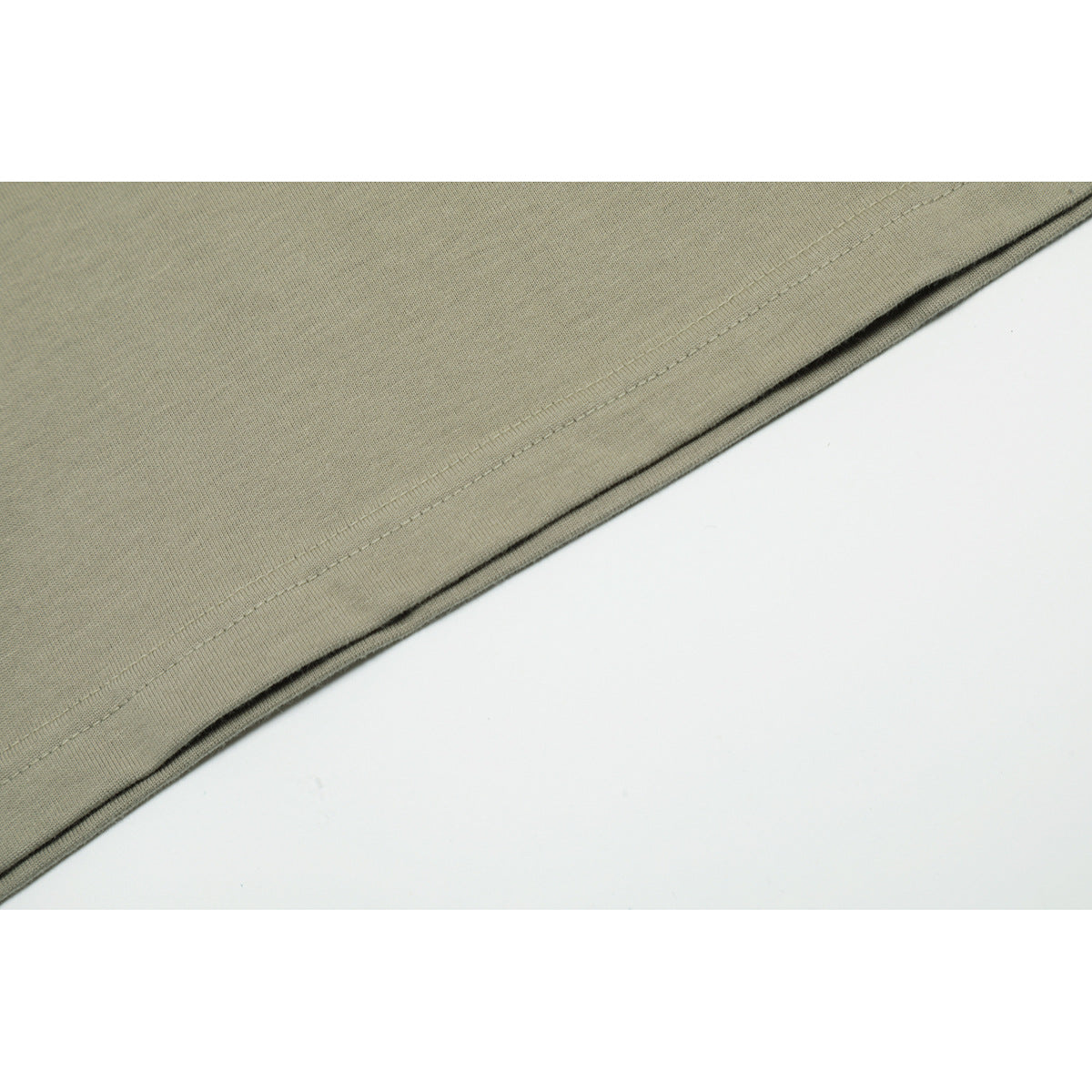 Close-up of the muted olive-gray T-shirt bottom hem with a straight line of stitching.