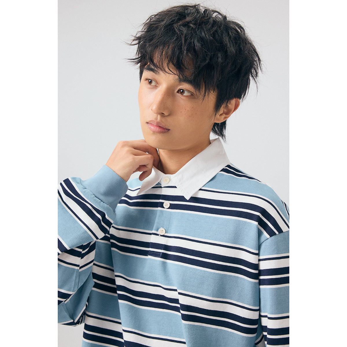 Close view of a model wearing a blue, white, and navy striped long-sleeve collared shirt.