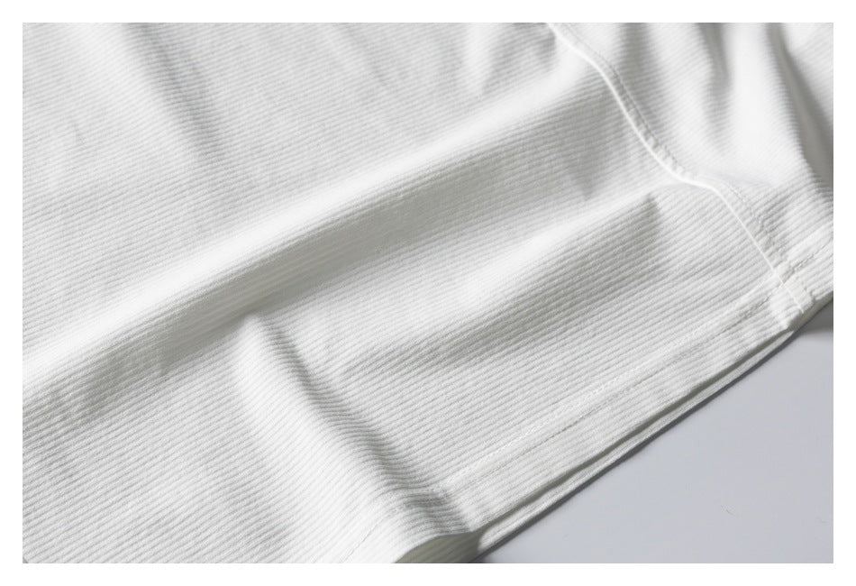 Close-up of white ribbed knit fabric with a folded edge and stitching.