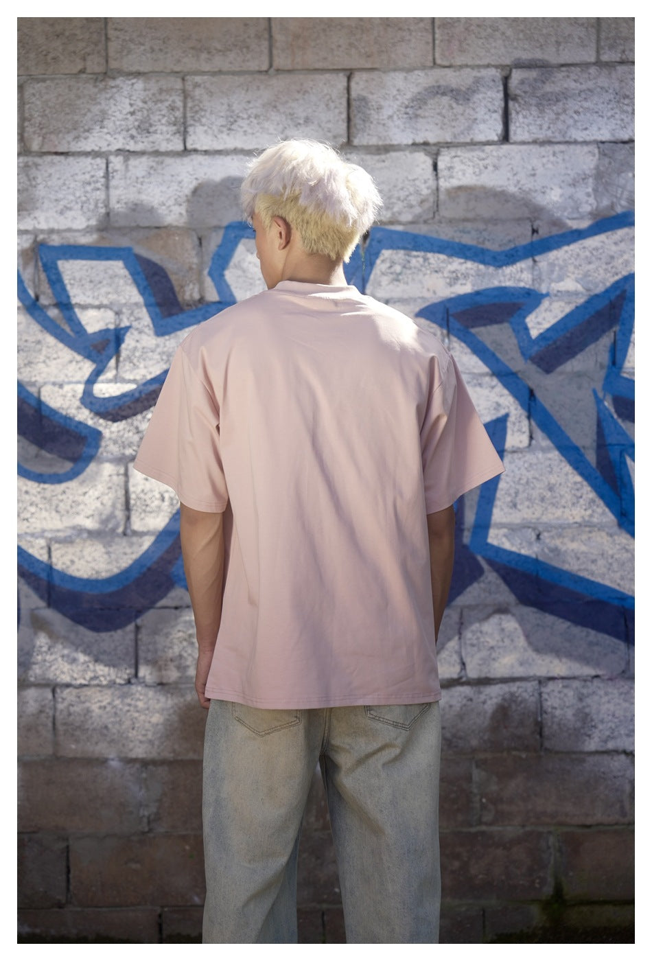 Back view of a model wearing a plain pale pink oversized T-shirt.