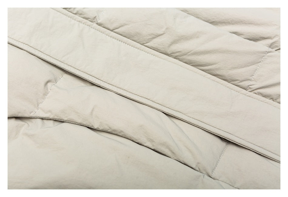 Close-up of pale beige garment panels with a long folded, stitched strip crossing diagonally.