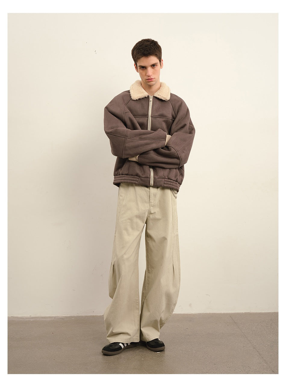 Front view of a model wearing a brown zip jacket with a cream plush collar and loose beige trousers.