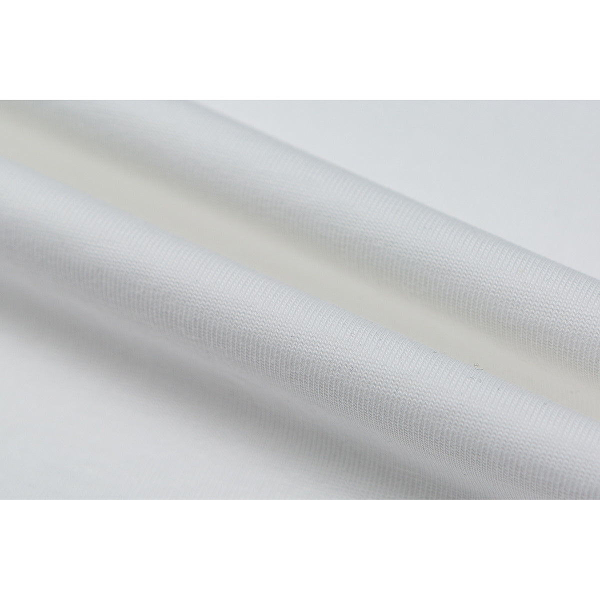 Close-up of white fabric draped in folds, showing its visible knit texture.