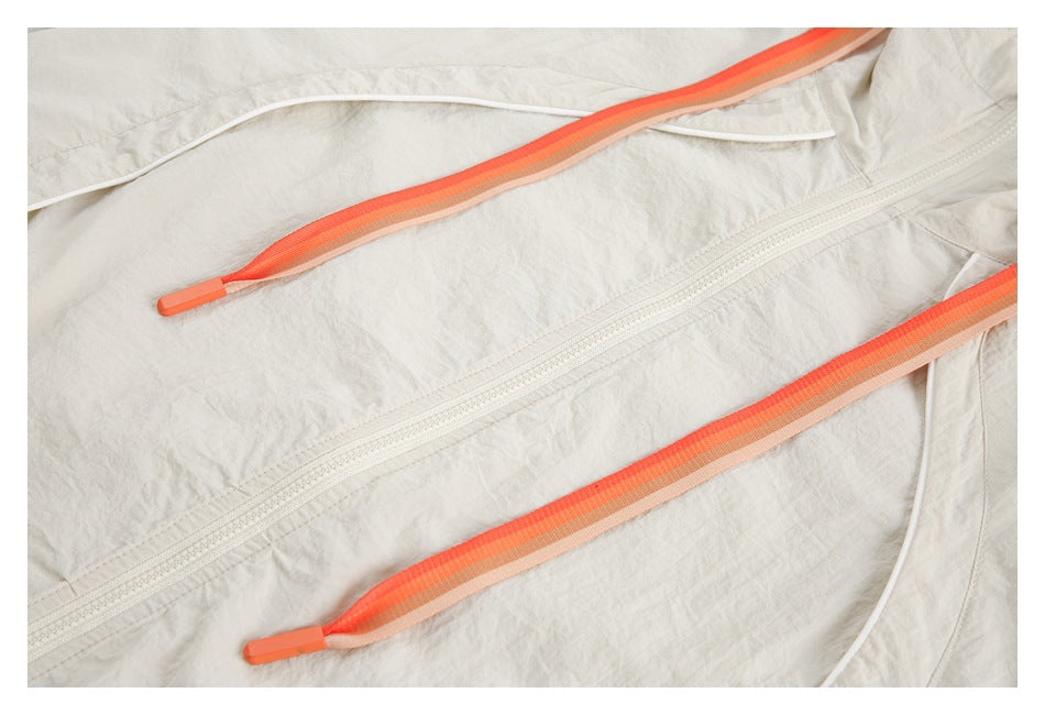 Close-up of a cream jacket front zipper and long orange-striped drawstrings.