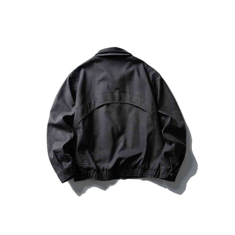 Back view of dark gray jacket with curved yoke seam, collar, snap cuffs and elastic hem, flat lay