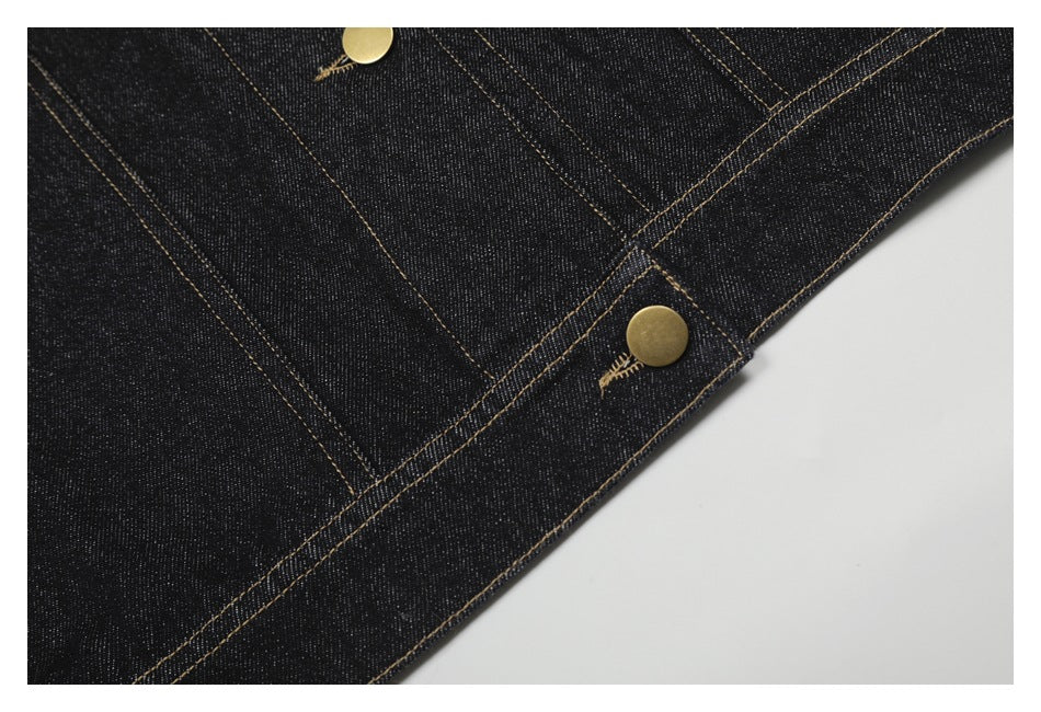 Close-up of a brass button and tan-stitched edge on dark indigo denim.