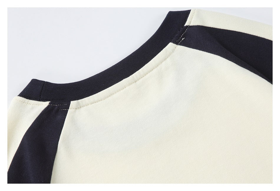 Close-up of a cream top's neckline and shoulder with dark navy contrast panels.