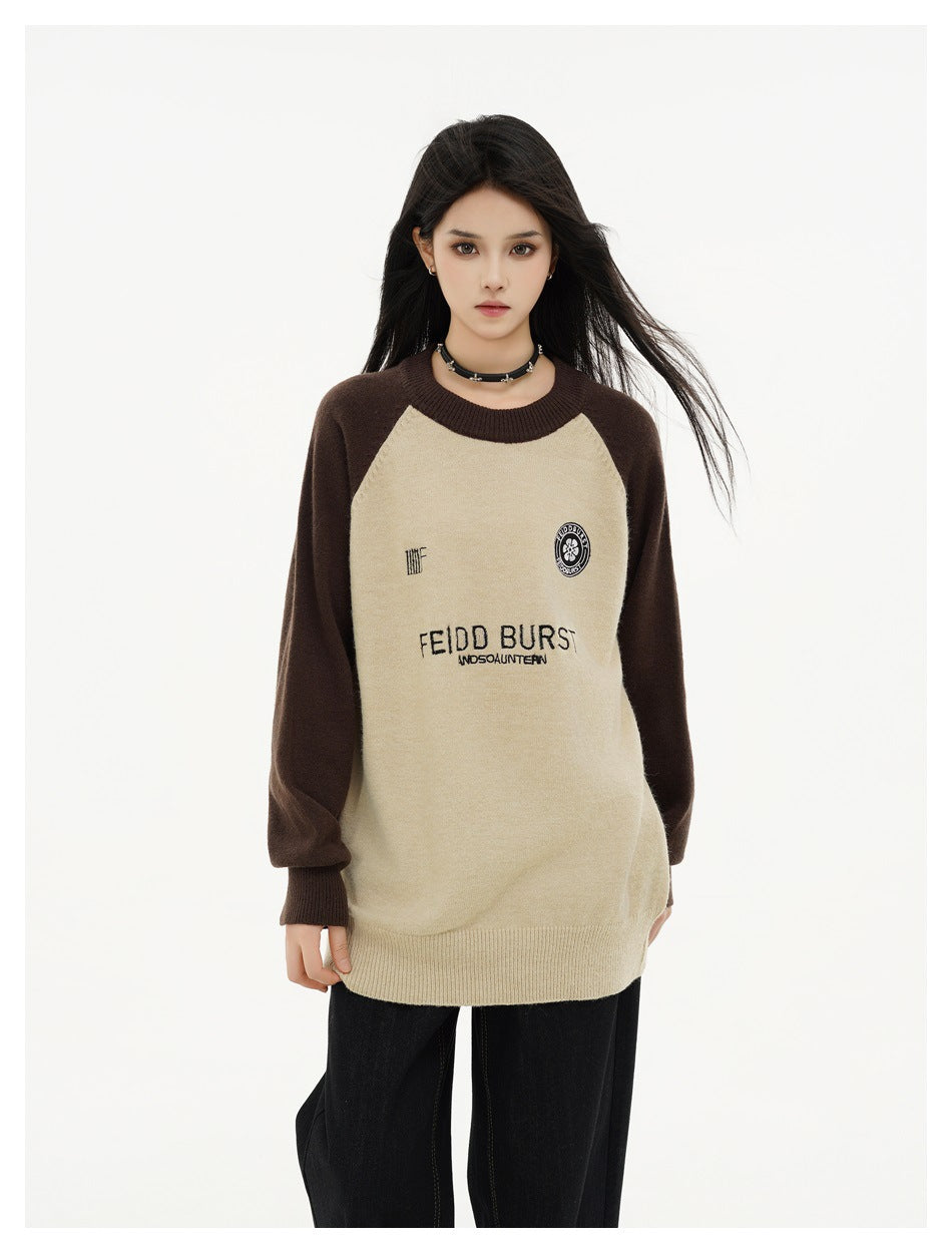 Front view of a model in an oversized cream and dark brown raglan sweater with chest lettering and emblems.