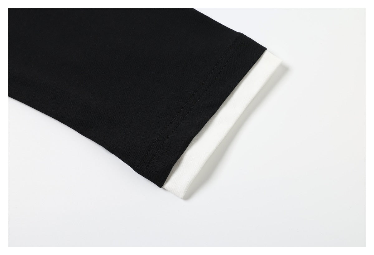 Close-up of a black sleeve hem layered over white fabric on a plain background.