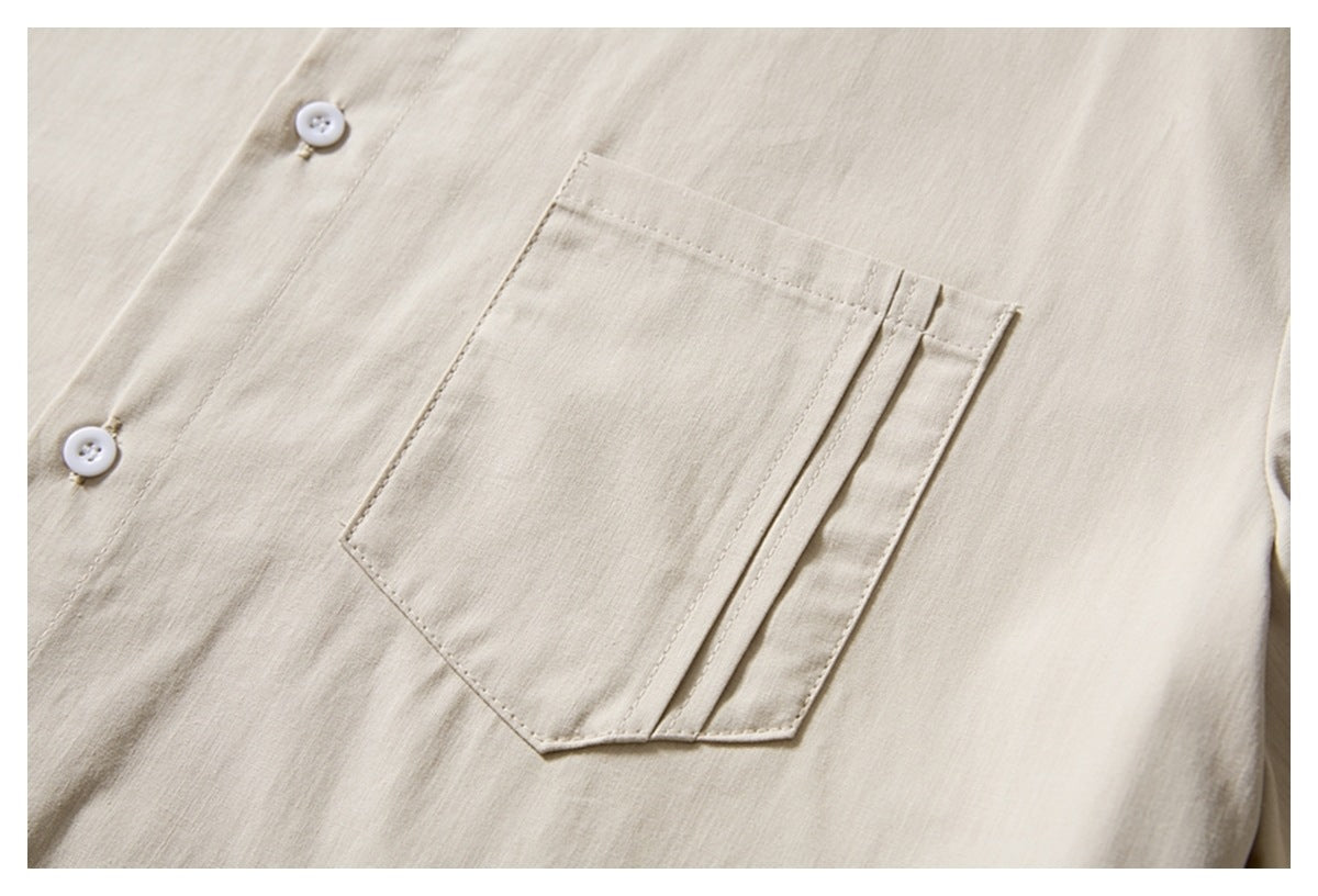 Close-up of an ivory shirt's angled chest pocket, decorative narrow trim, and white buttons.