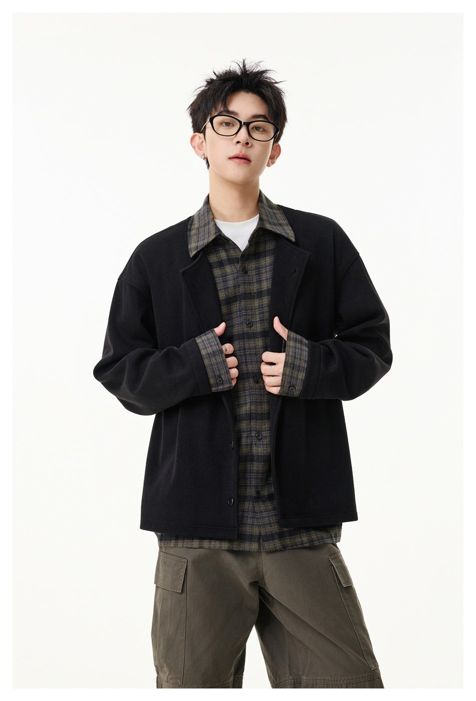 Model showing a black button-front jacket over a dark plaid shirt, holding the jacket edges.