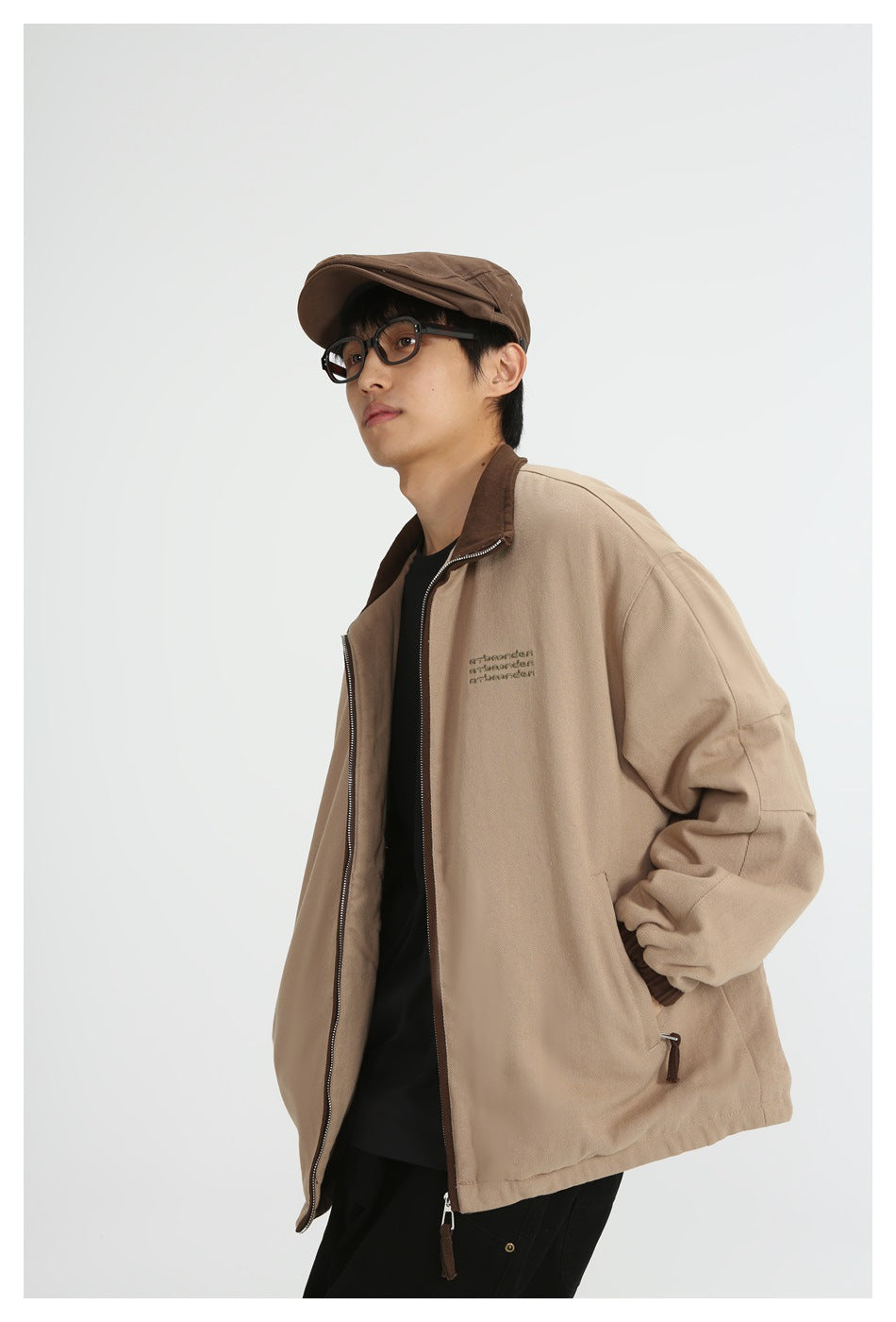 Angled view of a model wearing an open tan jacket with a dark brown collar and zip pockets.