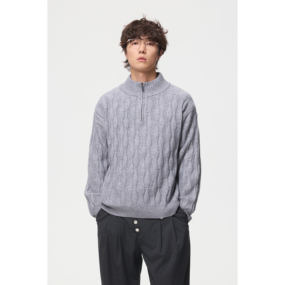 Front view of a model wearing a light gray cable-pattern quarter-zip sweater.