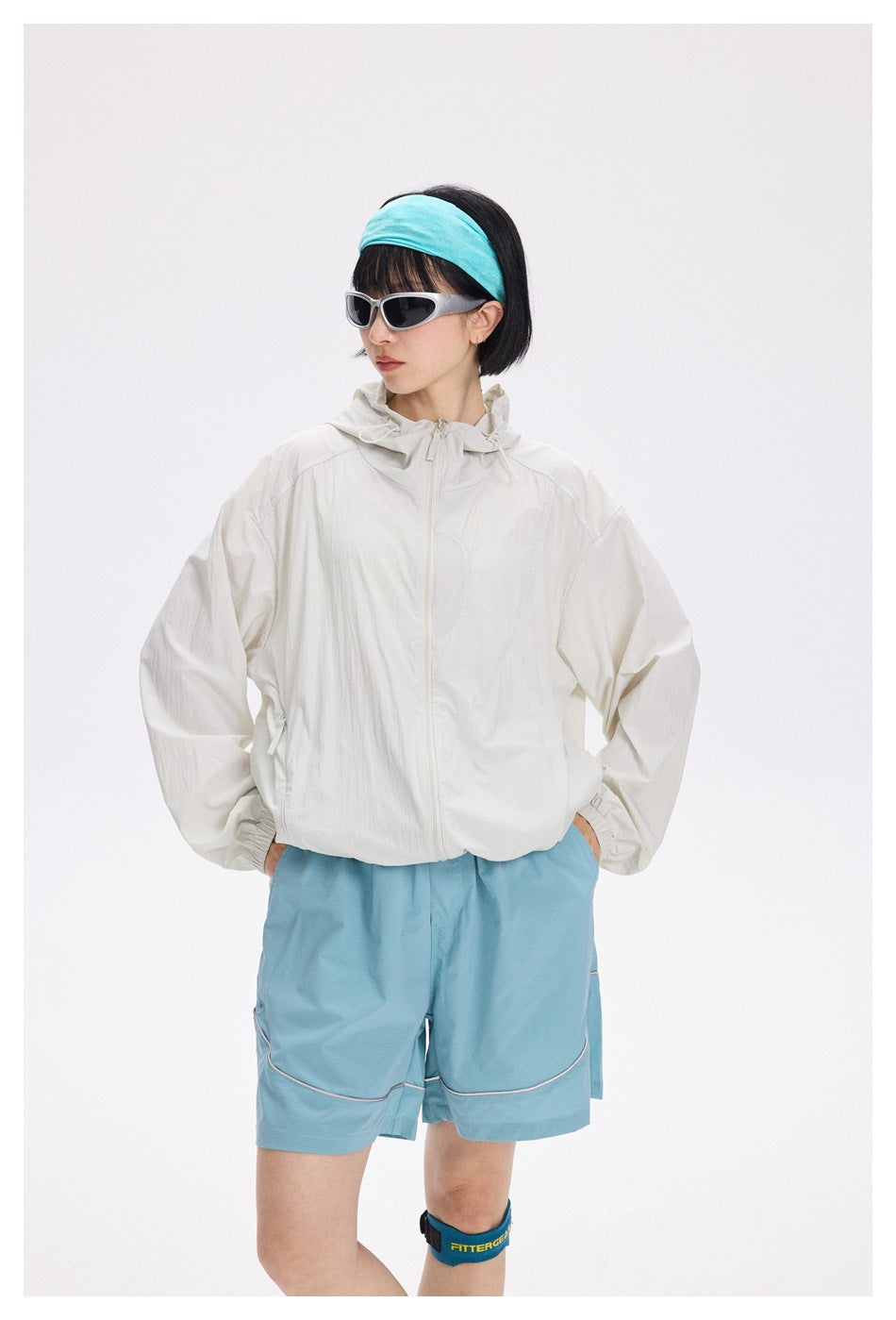 Front view of a model wearing an off-white zip-up hooded jacket and light blue shorts.