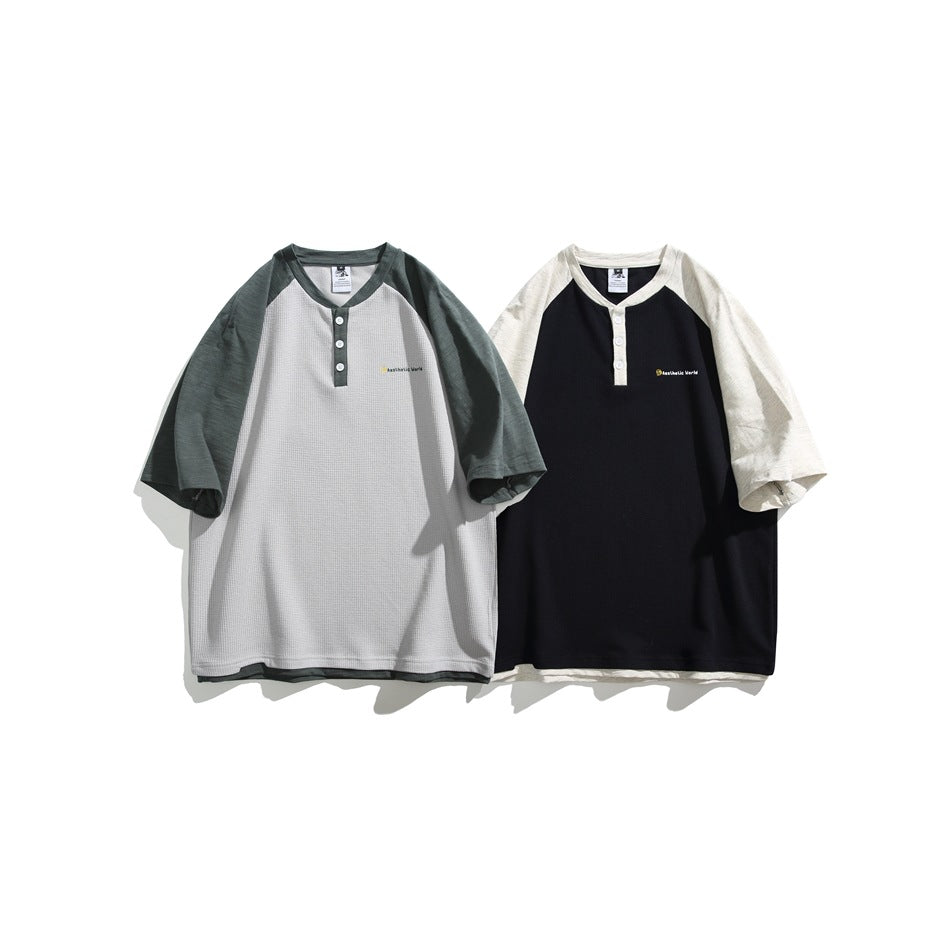 Two short-sleeve raglan henleys shown flat: one light gray with dark green sleeves, the other black with off-white sleeves.