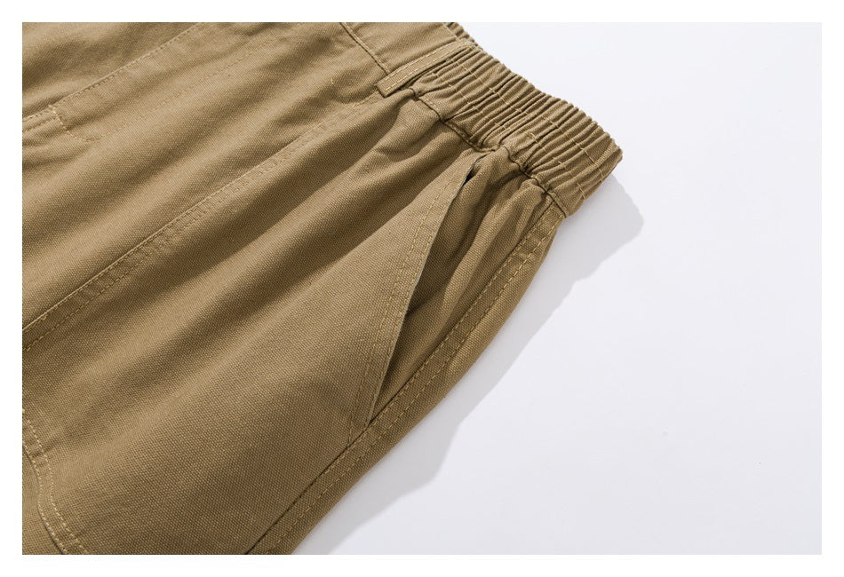 Close-up of tan shorts showing the elastic side waistband and angled front pocket.