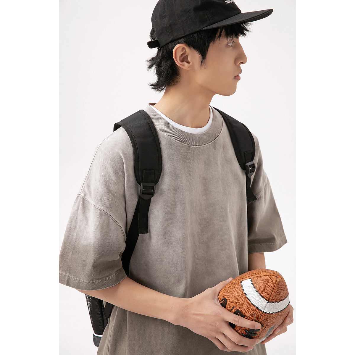 Model wearing an oversized taupe-gray washed T-shirt with dropped shoulders and short sleeves.