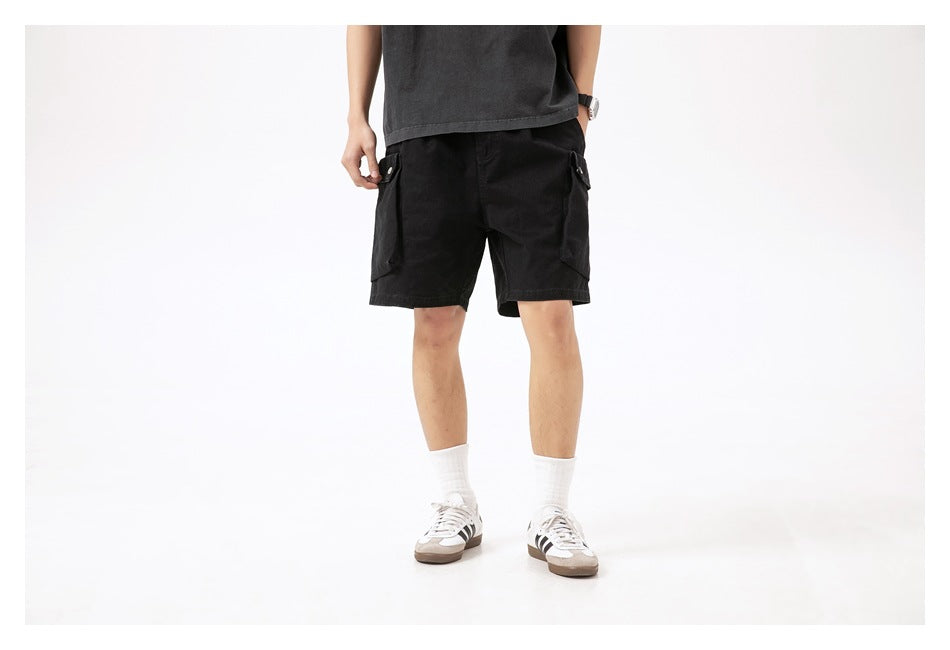 Back view of a model wearing black cargo shorts with large side flap pockets.