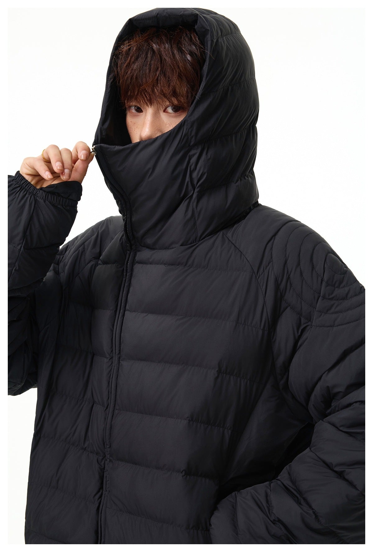 Close-up of the black puffer jacket's raised hood, high collar, front zipper, and quilted shoulder.