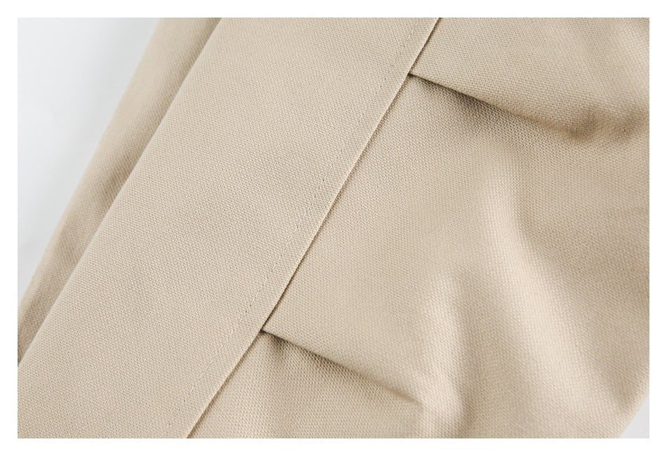 Close-up of beige coat fabric showing an overlapping flap and stitched seam.