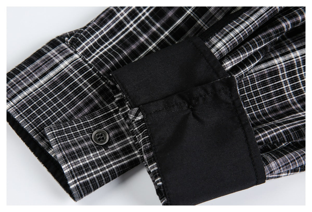 Close-up of a four-hole button and solid black cuff on black, white, and gray plaid fabric.