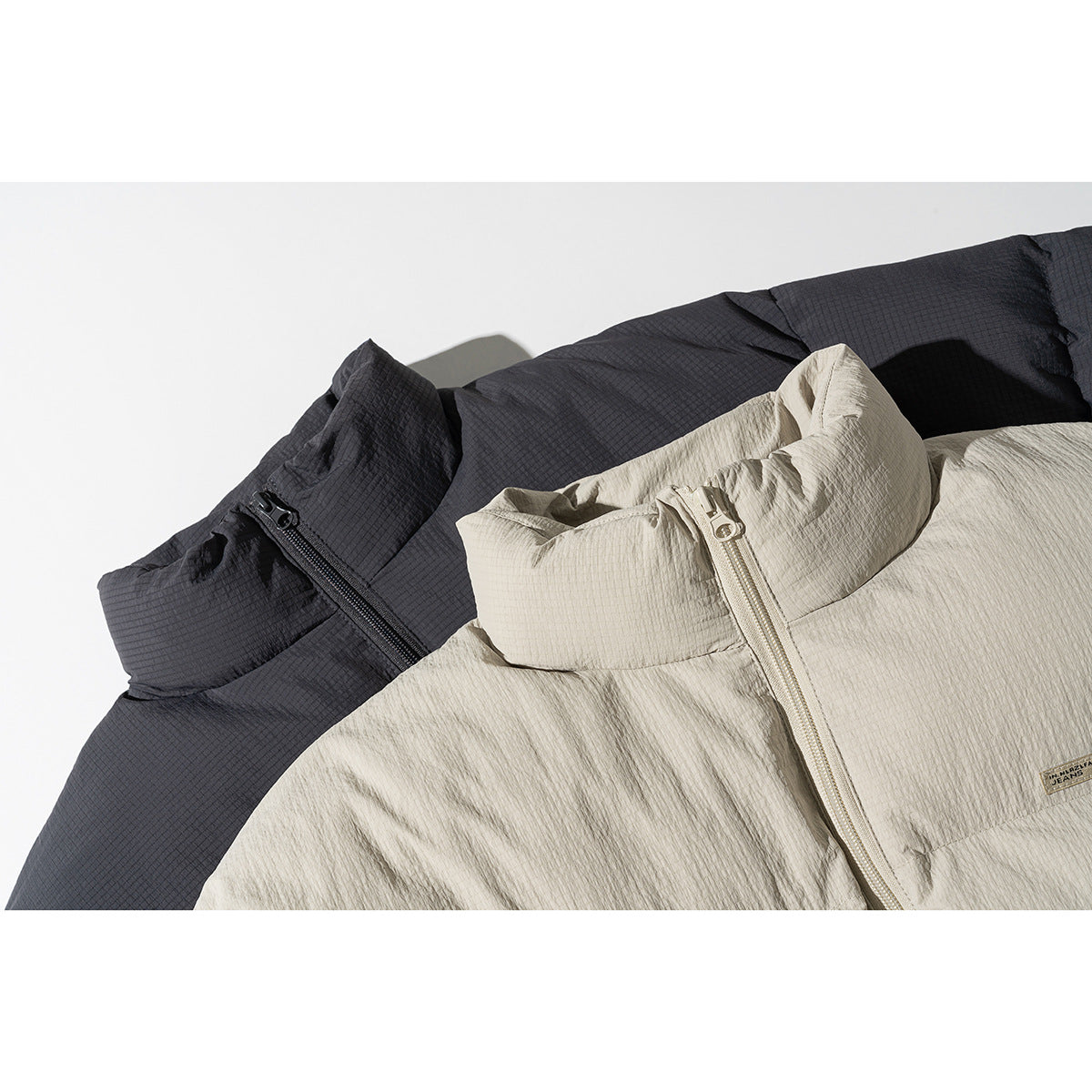 Close-up of charcoal and light beige padded jacket collars and front zippers.
