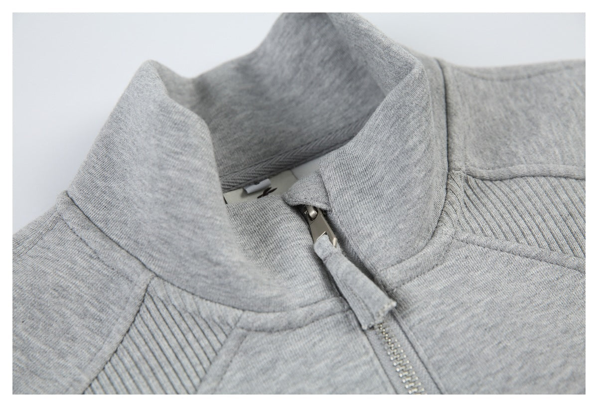 Close-up of the sweatshirt’s stand collar, zipper pull, and ribbed shoulder panel.