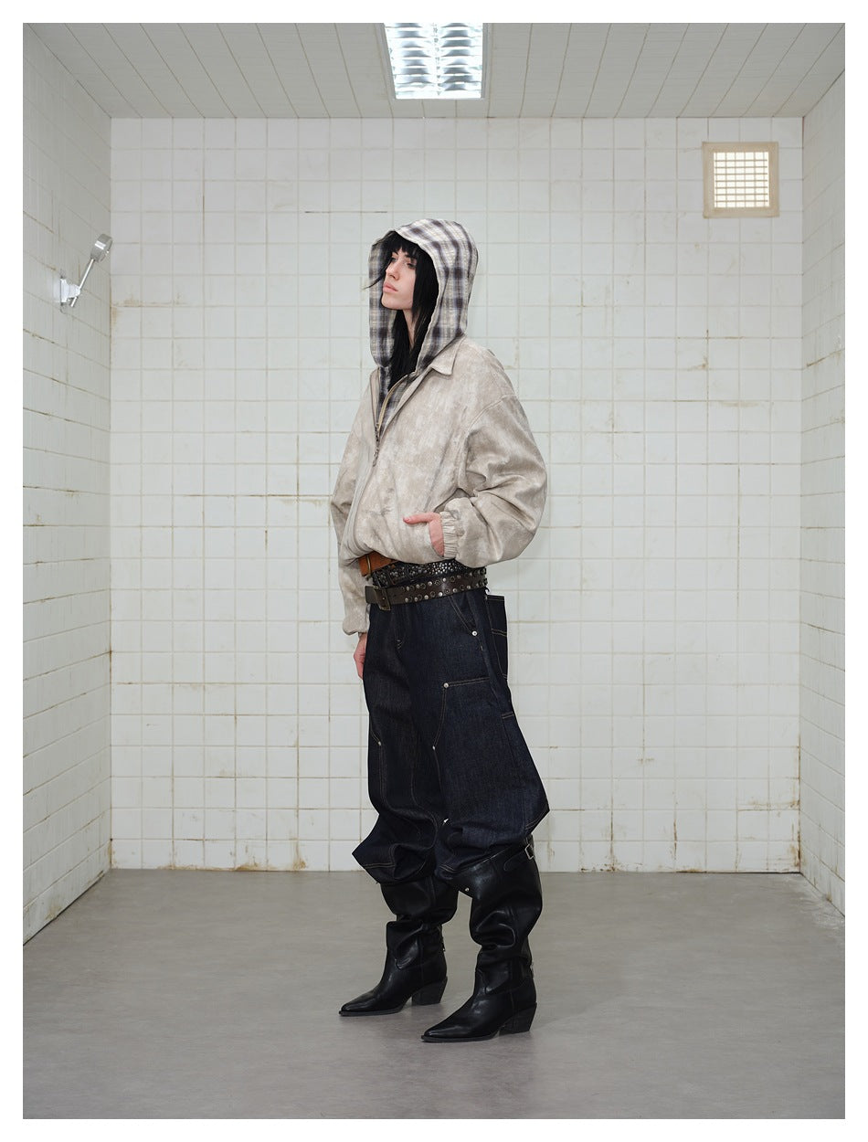 Side view of a model wearing a light beige mottled zip jacket with a plaid hood and dark baggy jeans.